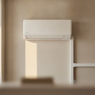 Een wandmodel airco boven een lichte binnenmuur, met de leidingdoorvoer eronder.